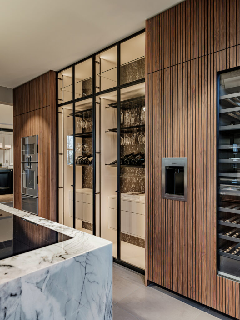 Luxe showroomkeuken van Tieleman Keukens met glaskasten, Mereno Seregno front in notenfineer kleur